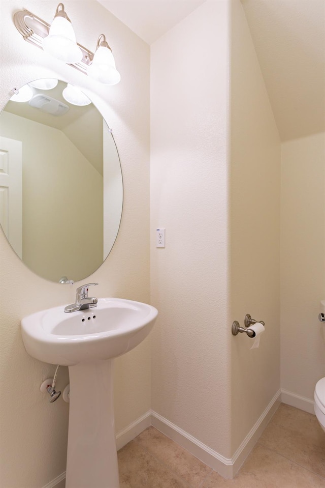 bathroom with toilet, tile patterned flooring, and vaulted ceiling