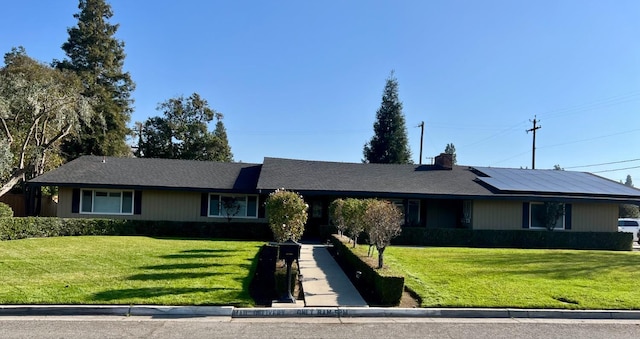 single story home with solar panels and a front lawn