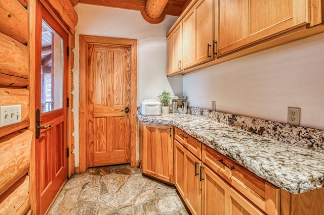 kitchen featuring beam ceiling, light stone counters, log walls, and wooden ceiling