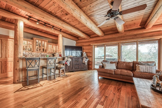 living room featuring light wood-type flooring, rail lighting, rustic walls, wooden ceiling, and beamed ceiling