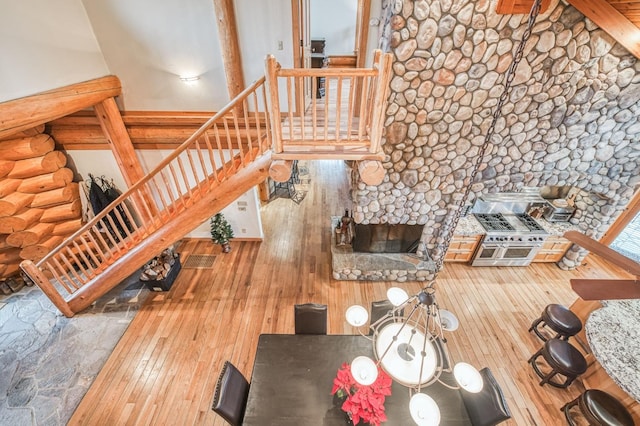 unfurnished living room with wood-type flooring, rustic walls, and a stone fireplace