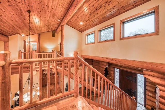 staircase with log walls, wooden ceiling, a notable chandelier, lofted ceiling, and hardwood / wood-style flooring