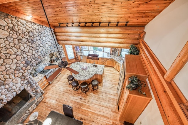 12755 Rusty Spur Ln, Clovis, CA 93619 - living area featuring rail lighting, wood ceiling, log walls, light wood-type flooring, and a stone fireplace
