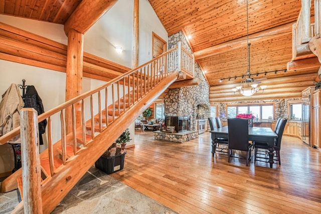 dining room with rustic walls, high vaulted ceiling, a notable chandelier, wood ceiling, and light wood-type flooring