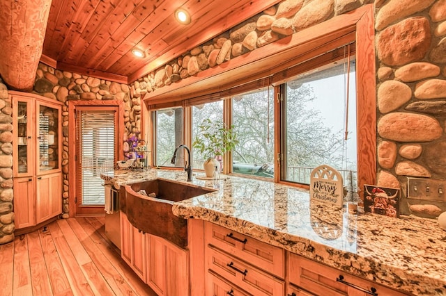 kitchen with light stone countertops, wooden ceiling, sink, and light hardwood / wood-style flooring