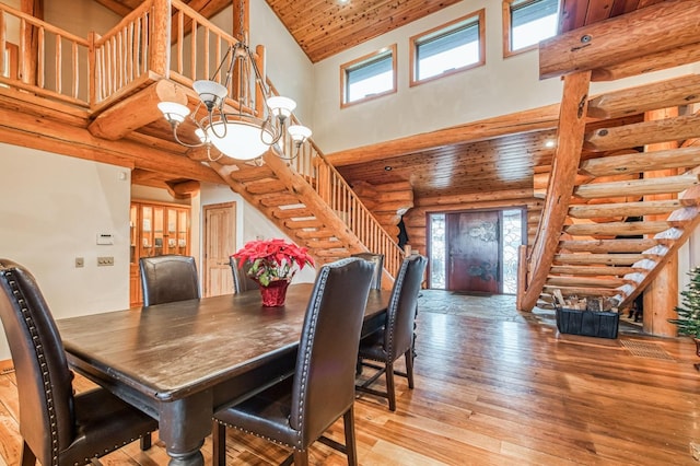 dining room featuring rustic walls, high vaulted ceiling, wooden ceiling, a notable chandelier, and light hardwood / wood-style floors