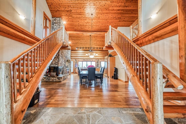 unfurnished dining area featuring rustic walls, high vaulted ceiling, a chandelier, and hardwood / wood-style flooring