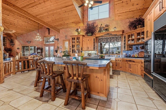 kitchen featuring tile counters, wooden ceiling, high vaulted ceiling, a kitchen bar, and light tile patterned flooring