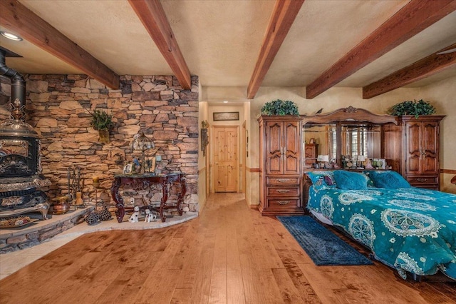 bedroom with beamed ceiling and light hardwood / wood-style floors