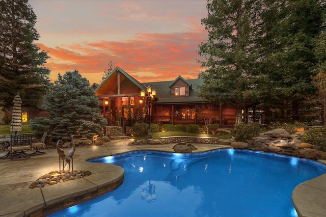 pool at dusk featuring a patio