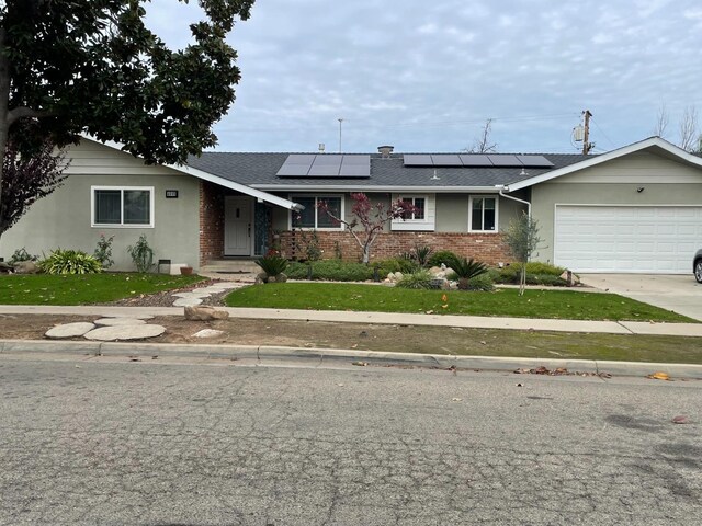 ranch-style house featuring solar panels, a garage, and a front lawn