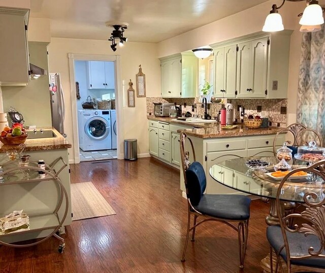 kitchen with sink, dark wood-type flooring, independent washer and dryer, kitchen peninsula, and decorative backsplash