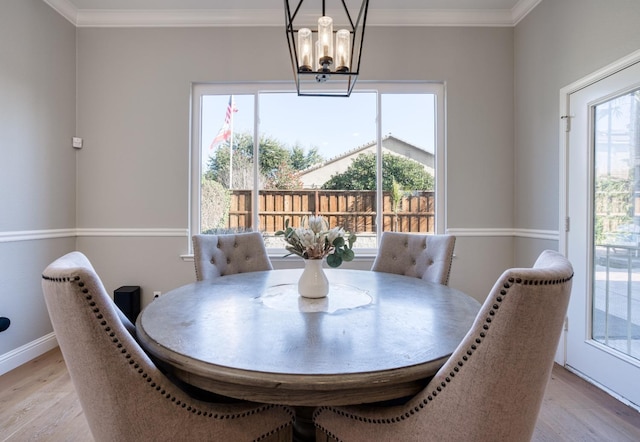 dining room with ornamental molding, light hardwood / wood-style flooring, a wealth of natural light, and a notable chandelier