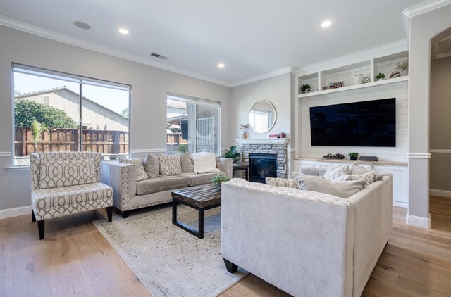 living room with a fireplace, light wood-type flooring, and crown molding