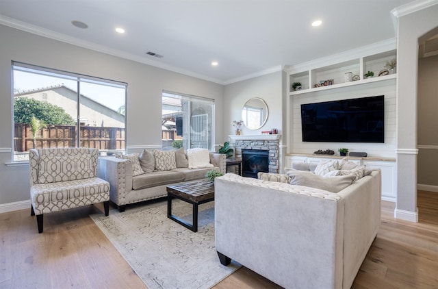 living room with crown molding, a fireplace, and light wood-type flooring