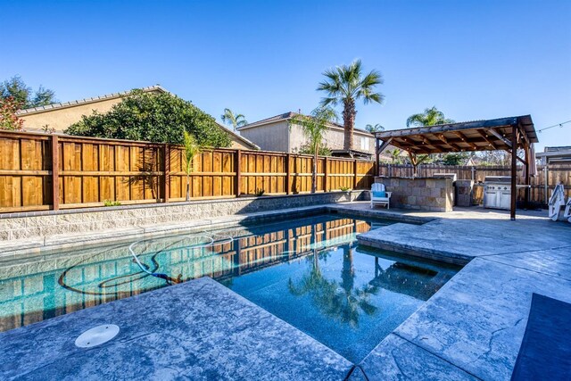 view of pool with area for grilling, an in ground hot tub, and a grill