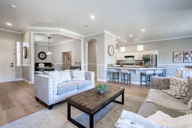 living room featuring crown molding, light hardwood / wood-style flooring, and an inviting chandelier