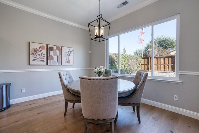 dining room with crown molding, hardwood / wood-style flooring, and a notable chandelier