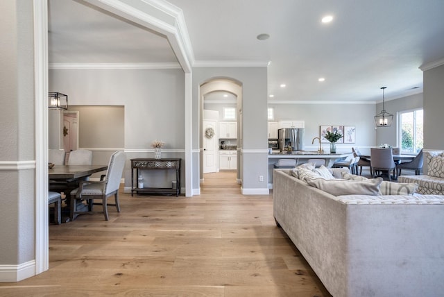 living room featuring light wood-type flooring, ornamental molding, and sink