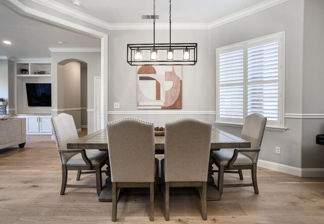 dining area featuring built in shelves, light hardwood / wood-style floors, and ornamental molding