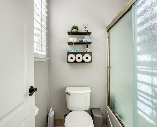 bathroom with shower / bath combination with glass door and toilet