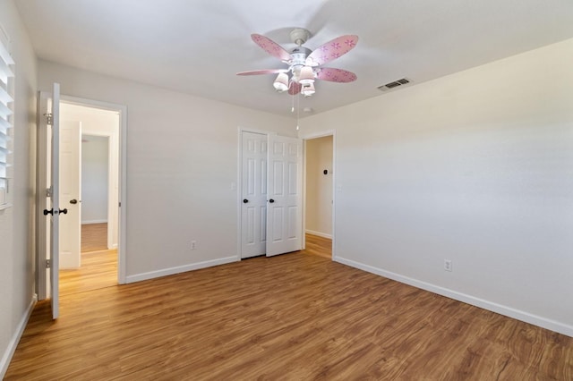 unfurnished bedroom featuring hardwood / wood-style floors, a closet, and ceiling fan