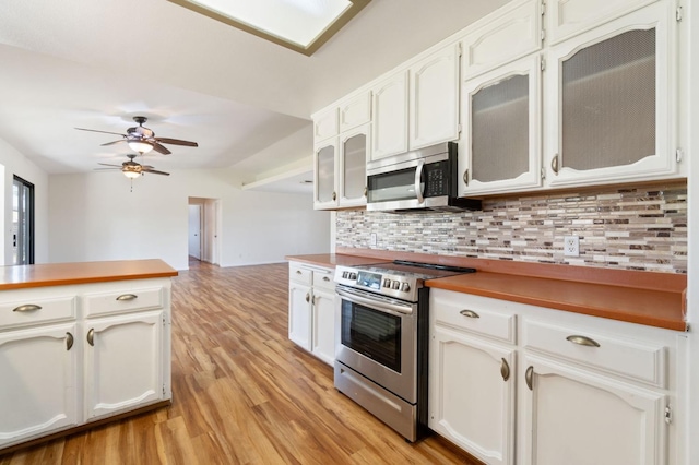 kitchen with white cabinets, decorative backsplash, ceiling fan, light hardwood / wood-style floors, and stainless steel appliances