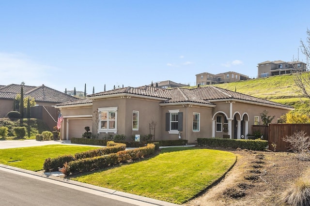 mediterranean / spanish home with a garage and a front lawn