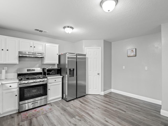 kitchen with a textured ceiling, white cabinetry, stainless steel appliances, and light hardwood / wood-style flooring