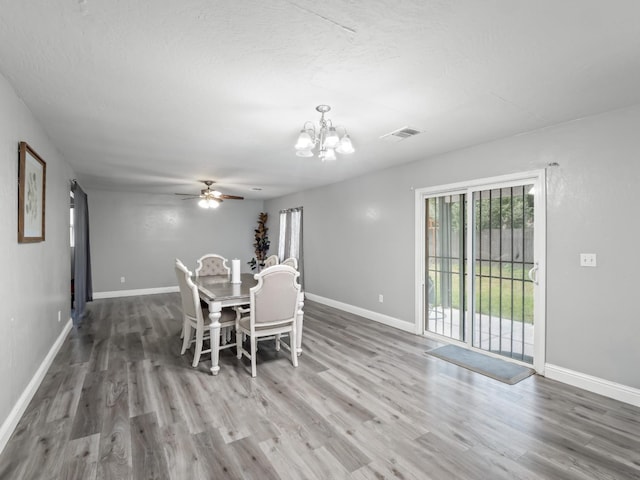 dining space featuring a wealth of natural light, ceiling fan with notable chandelier, and hardwood / wood-style flooring