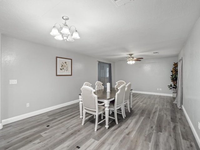 dining area with wood-type flooring and ceiling fan with notable chandelier