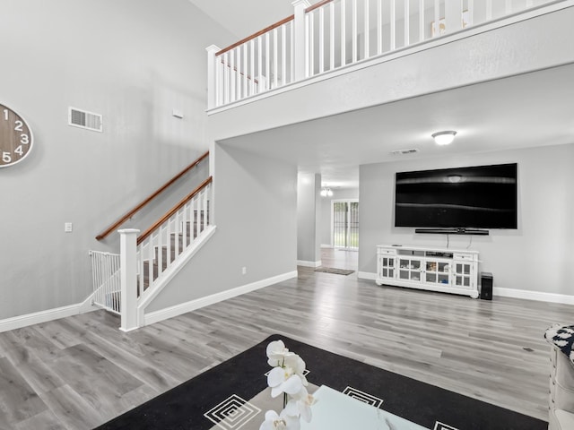 living room with wood-type flooring and a towering ceiling