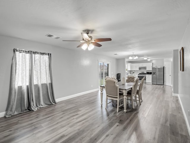 dining area with hardwood / wood-style flooring and ceiling fan with notable chandelier