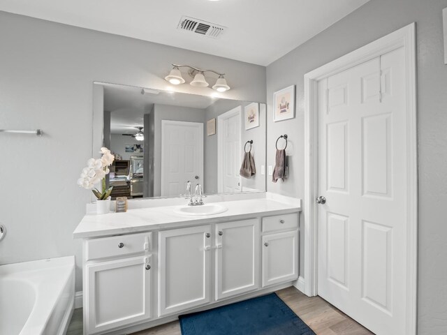 bathroom featuring a tub, ceiling fan, hardwood / wood-style floors, and vanity