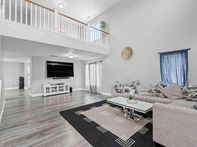 living room with a towering ceiling and wood-type flooring