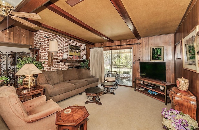 living room featuring beam ceiling, ceiling fan, light colored carpet, and wood walls