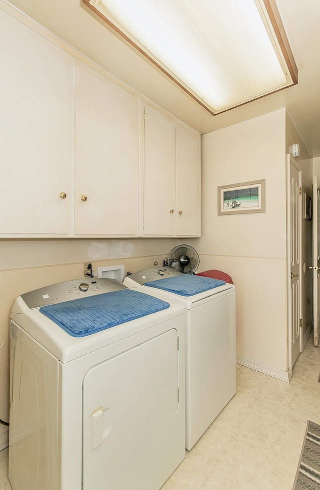 laundry area with separate washer and dryer and cabinets