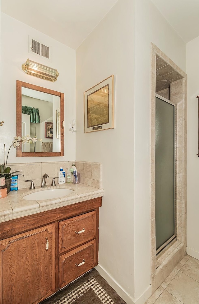 bathroom with backsplash, tile patterned flooring, vanity, and an enclosed shower