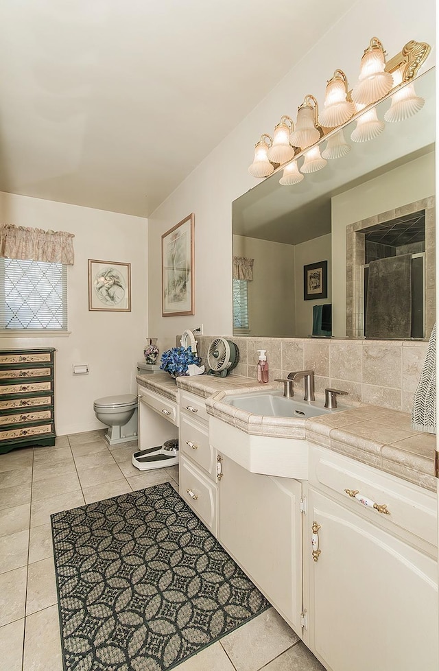 bathroom featuring toilet, vanity, tasteful backsplash, and tile patterned floors