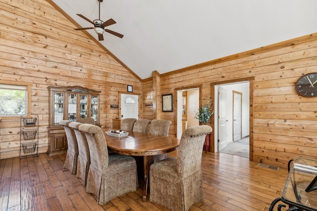 dining area with ceiling fan, wood-type flooring, and high vaulted ceiling