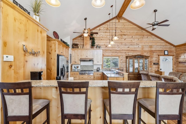 kitchen with kitchen peninsula, a kitchen breakfast bar, light brown cabinets, high vaulted ceiling, and stainless steel fridge with ice dispenser