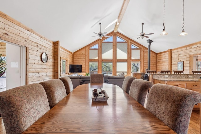 dining room with vaulted ceiling with beams, wood walls, wood-type flooring, and ceiling fan