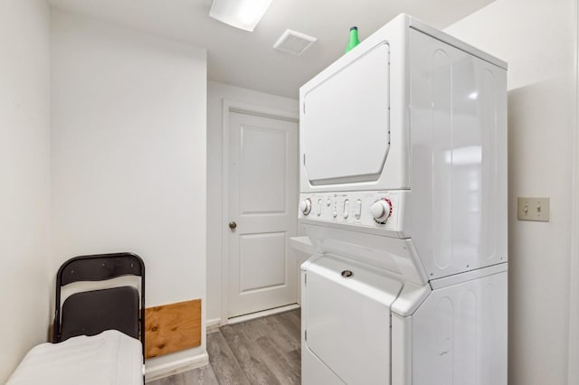 laundry room featuring stacked washer and clothes dryer and light wood-type flooring