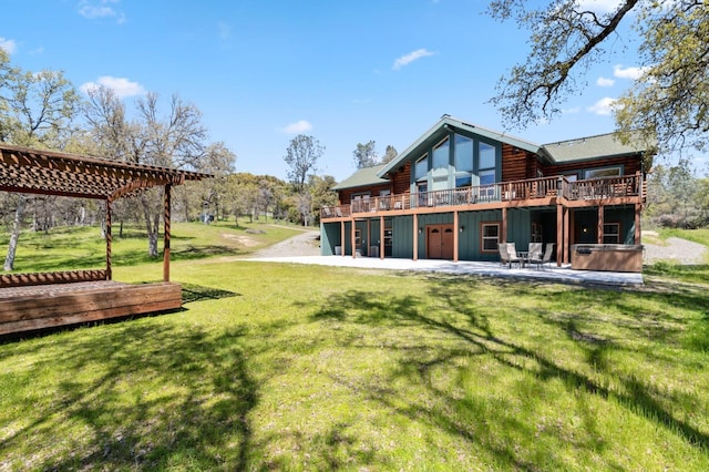 rear view of property with a lawn, a patio area, a pergola, and a wooden deck