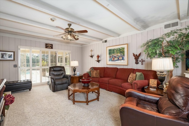 carpeted living room with ceiling fan and beamed ceiling