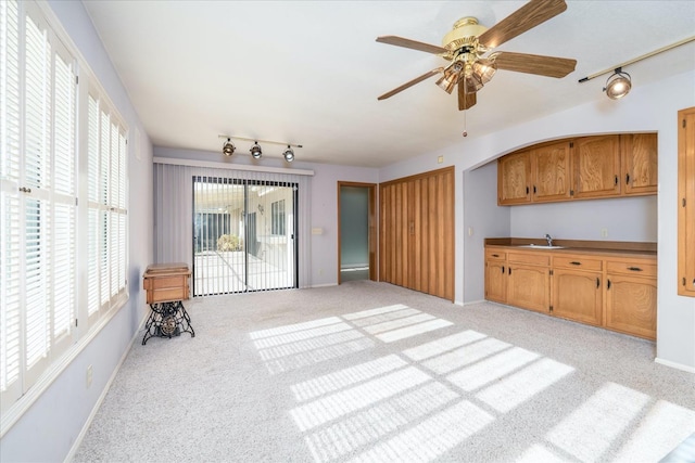 unfurnished living room featuring light colored carpet, ceiling fan, and sink