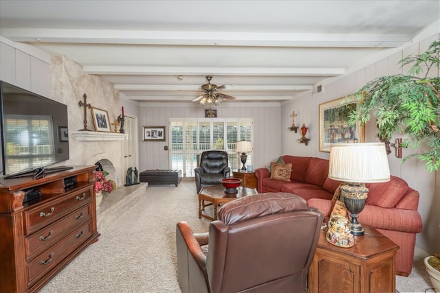 living room with beamed ceiling, a large fireplace, light colored carpet, and ceiling fan