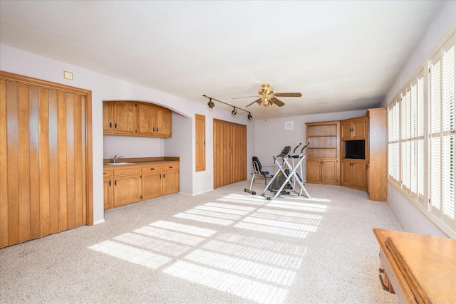 exercise area featuring rail lighting, light colored carpet, ceiling fan, and sink