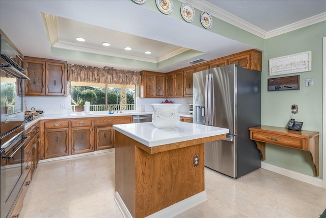 kitchen featuring a center island, crown molding, appliances with stainless steel finishes, and a tray ceiling