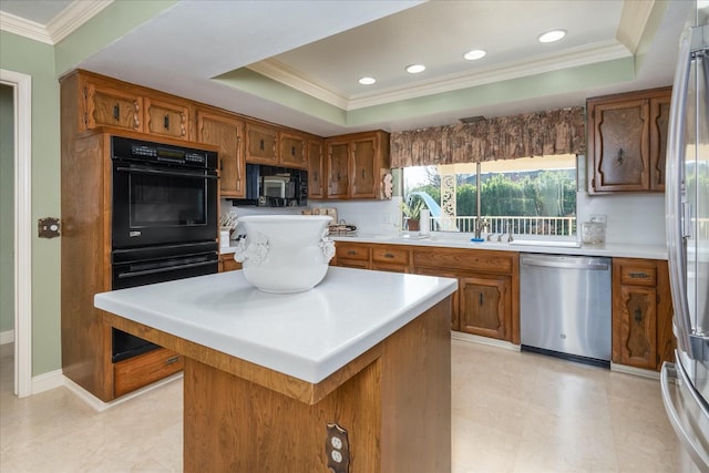 kitchen with a tray ceiling, crown molding, a kitchen island, and black appliances